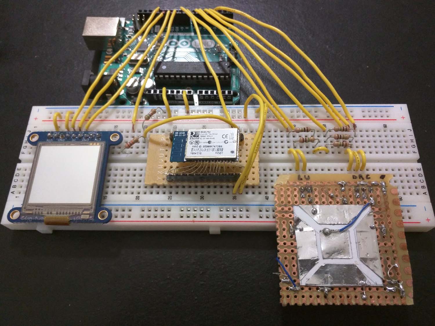 The prototyping setup for the smartwatch. On the breadboard from left to right: SHARP Memory LCD, Bluetooth module, homemade capacitive touch testing pad